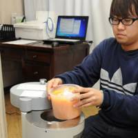 ATOMTEX 101: A staff member at the Citizen\'s Radioactivity Measurement Station in Setagaya Ward, Tokyo, demonstrates how to use an ATOMTEX machine to measure radioactive cesium in food items in mid-December. | SATOKO KAWASAKI
