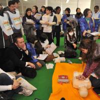 Crash course: Foreign residents of Tokyo take part in an emergency drill in Shibuya Ward on Friday. | YOSHIAKI MIURA