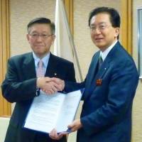 Working together: Akita Gov. Norihisa Satake (left) appears with Iwate Gov. Takuya Tasso at the Iwate Prefectural Government headquarters in Morioka on Tuesday after they signed an agreement on tsunami debris. | KYODO