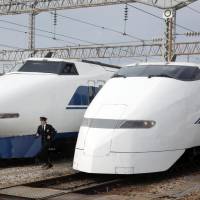 Last hurrah: A JR West official runs between a 100 series bullet train (left) and a 300 series at a car shed in Hakata, Fukuoka Prefecture, on Wednesday. The two series will be taken out of service on March 16. | KYODO