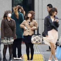 Bad hair day: Strong southerly winds hit Friday in the Marunouchi office district of central Tokyo. | KYODO