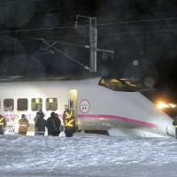 Off the rails: The front car of a bullet train on the Akita Shinkansen Line lies in heavy snow following its derailment Saturday in the city of Daisen, Akita Prefecture. | KYODO