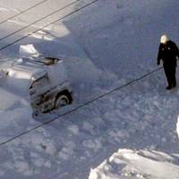 Seeking answers: An investigator walks Sunday afternoon near the car in which 40-year-old Kazuyo Miyashita and her three children died of carbon monoxide poisoning while the vehicle was trapped under snow the previous day in Nakashibetsu, Hokkaido. | KYODO