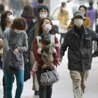Haz-masks: Fukuoka residents venture outdoors wearing masks Saturday to protect themselves against a cloud of yellow sand that is drifting across from China. | KYODO