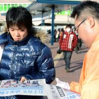 Read all about it: An Iwate Nippo official hands out an extra Monday in front of Matsuyama Station in Ehime Prefecture. | KYODO