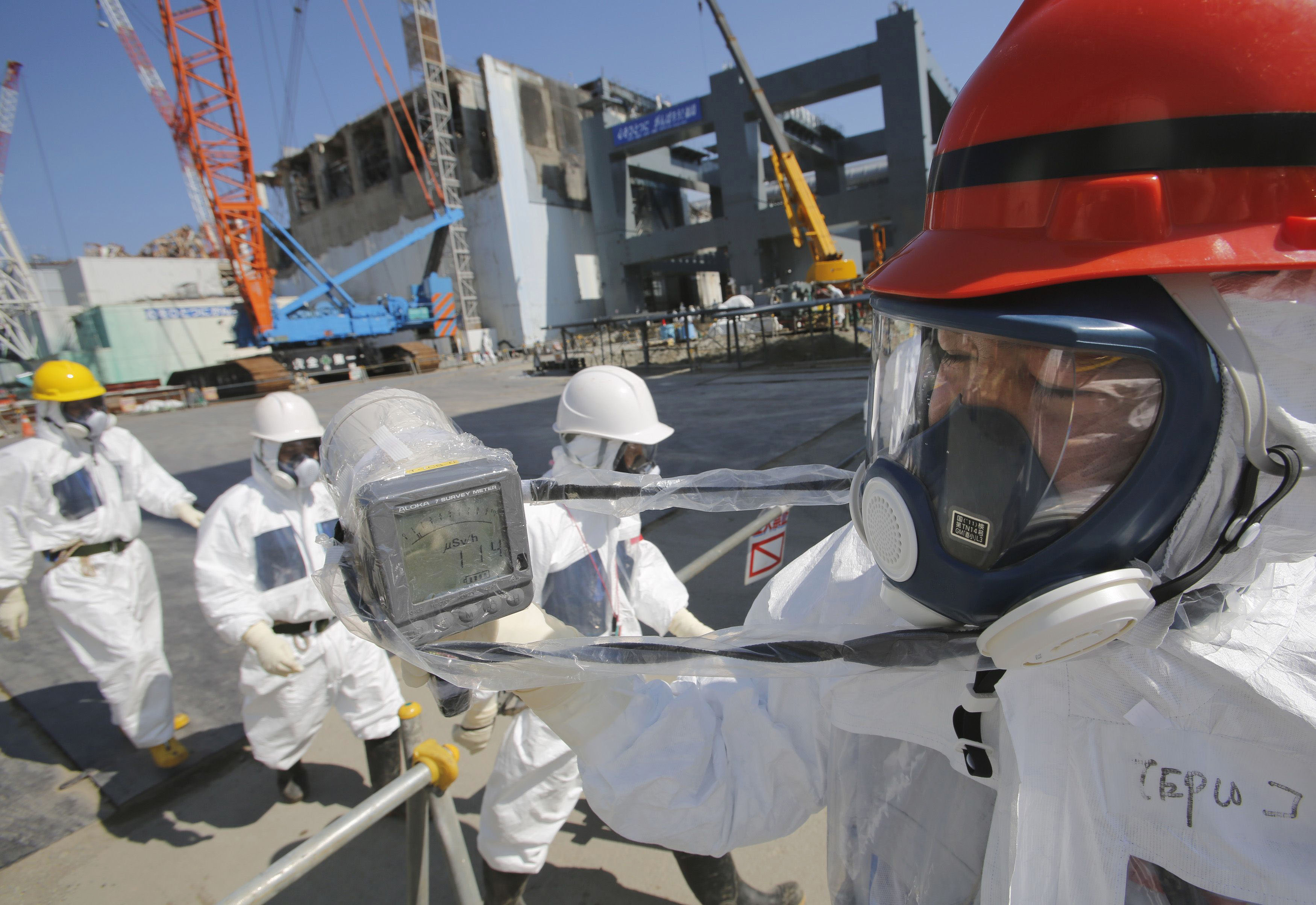Hazard pay: A worker at the Fukushima No. 1 nuclear complex gets a radiation reading of 114 microsieverts per hour on March 6 near reactor 4, which stands surrounded by cranes next to the concrete foundations for a storage facility for melted fuel rods. | POOL
