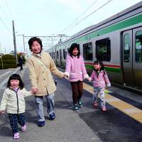 A woman and her grandchildren get off at Hamayoshida Station in Watari, Miyagi Prefecture, after a damaged part of the Joban Line resumed service Saturday for the first time since the March 2011 quake and tsunami. | KYODO