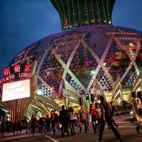 Place your bets: Pedestrians cross an intersection in front of the Casino Grand Lisboa, operated by SJM Holdings Ltd., in Macau in February. Diet members are considering submitting a bill to legalize casinos like this. | BLOOMBERG