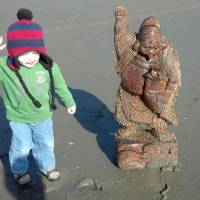 Lucky find: A child on a beach in Washington state poses Monday next to a statue of Ebisu that apparently was swept into the sea by the 2011 tsunami. | ALISON NELSON/KYODO