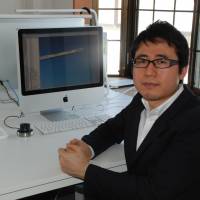One-man band: Keita Yagi, founder of Bsize Inc., is interviewed at his office in Odawara, Kanagawa Prefecture, on March 19. Above his computer is his award-winning Stroke lamp, which emits light from the end of a tube wrapped around its frame. Venture manufacturers on the rise