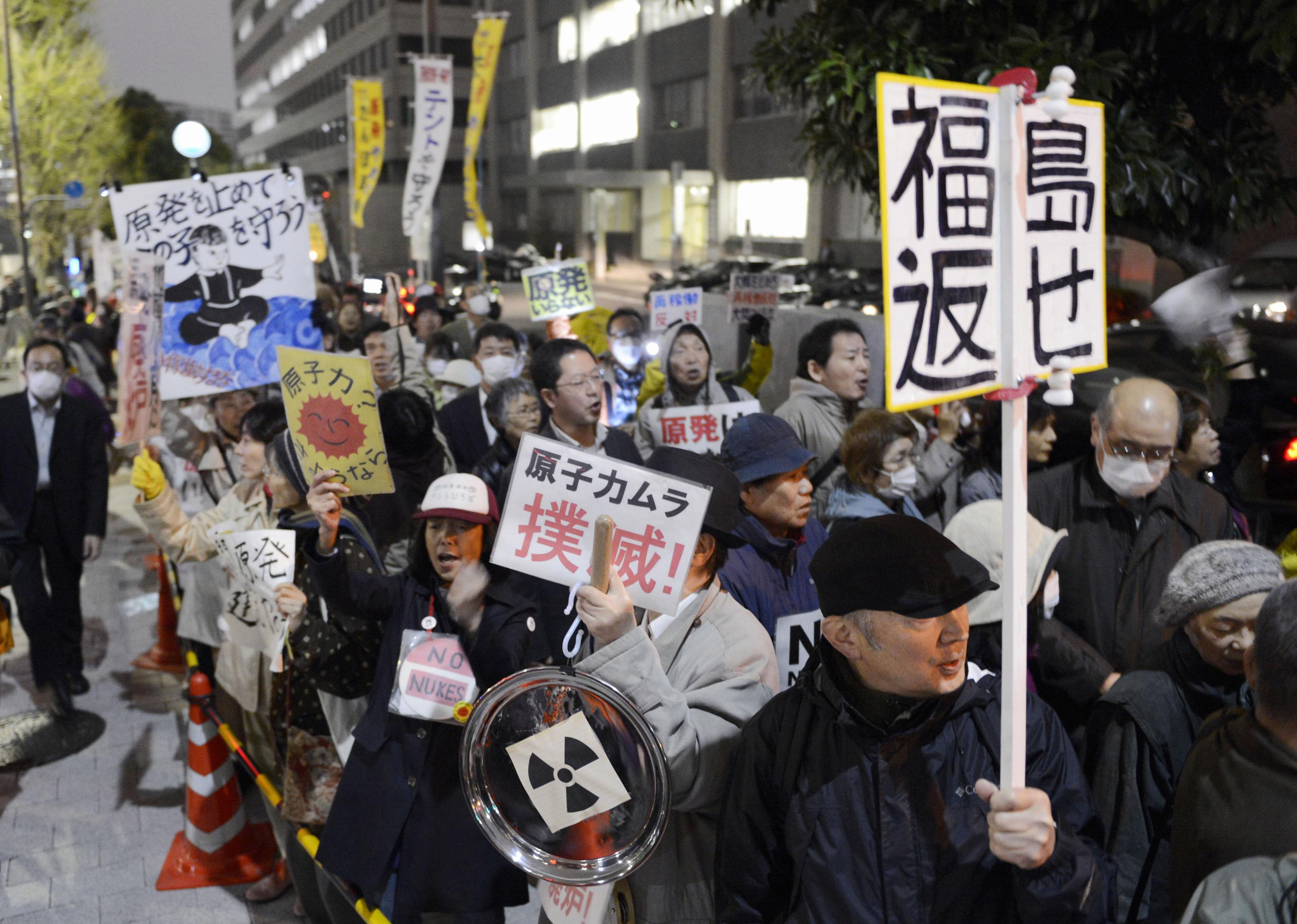 Undeterred: Participants march through Tokyo's Nagata-cho political hub Friday evening urging the government to abandon nuclear power, continuing a weekly demonstration that has lasted a year. | KYODO