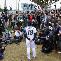 Media throng: Reporters surround Hokkaido Nippon Ham Fighters pitcher Yuki Saito on the first day of spring training on Tuesday in Nago, Okinawa Prefecture. Nine NPB clubs are holding camp in Okinawa. | KYODO PHOTO