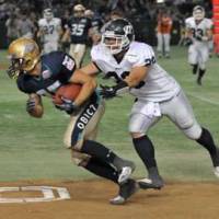On the move: Obic Seagulls receiver Ryoma Hagiyama (left) runs after a first-quarter catch as Panasonic Electronic Works Impulse linebacker Hiroshi Ishihara closes in on a tackle in the Japan X Bowl on Monday at Tokyo Dome. | HIROSHI IKEZAWA PHOTOS