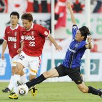 In the thick of it: Gamba\'s Yasuhito Endo stretches to compete for the ball with Urawa\'s Yuki Abe on Sunday. | KYODO PHOTO