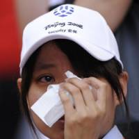 In tears: A security staffer cries after hearing that Liu Xiang has pullled out of the Olympics on Monday in Beijing. | AP PHOTO