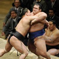 Off the mark: Harumafuji (left) heaves Kotoshogiku out of the ring as Asashoryu watches on at the New Year Grand Sumo Tournament on Thursday. | KYODO PHOTO