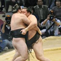 Weekend warrior: Hakuho (right) eases Aran out of the ring at the Kyushu Grand Sumo Tournament on Sunday. | KYODO PHOTO