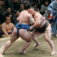 Brute force: Hakuho and rank-and-filer Tamawashi (left) square off on the eighth day of the New Year Grand Sumo Tournament at Ryogoku Kokugikan. | KYODO PHOTO
