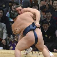To the limit: Harumafuji (rear) is pushed onto the straw bales by Goeido during their bout at the Kyushu Grand Sumo Tournament on Monday. | KYODO