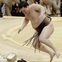 Watch out below: Hakuho jumps out of the falls out of the ring after defeating Myogiryu on Wednesday. | KYODO