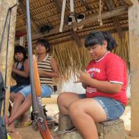 Digital tribe:  Teenage girls make jewelry to sell to visitors in Lapetanha, one of the forested Brazilian hamlets where the Paiter Surui people live, in December. | THE WASHINGTON POST