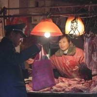 Easy pickings: A street vendor sells pork from a market stall in Shanghai in February. | BLOOMBERG