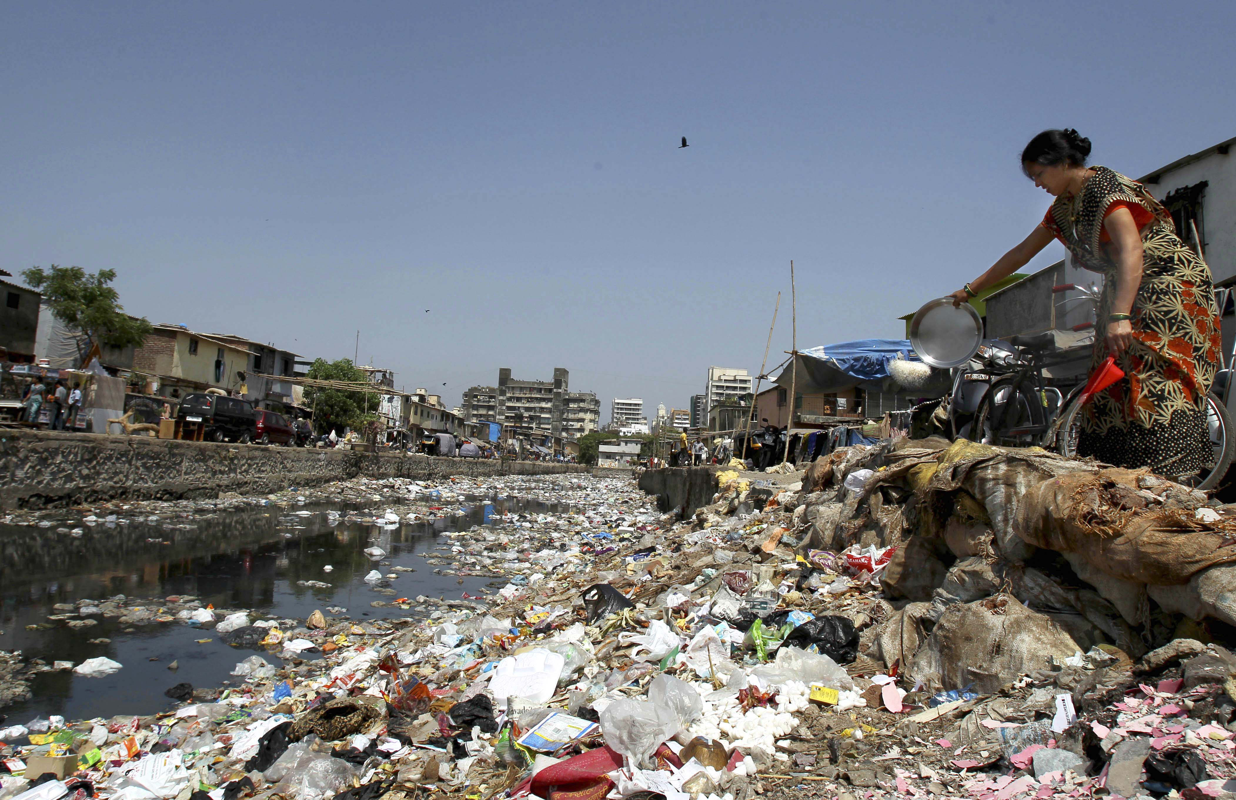 Just a litter bit: A woman throws waste into a garbage-choked Mumbai canal on Monday. | AP