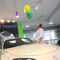 Looking up: A Mazda salesman ties balloons to a 2008 MX-5 Miata at a Mazda dealership in Port Richey, Fla., in April. | BLOOMBERG PHOTO