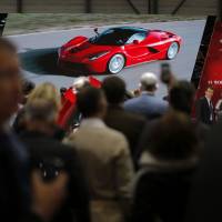 Yen for speed: Visitors watch a video of the new Ferrari La Ferrari (F150) on Ferrari SpA\'s stand at the 83rd Geneva International Motor Show in Geneva on March 6. | BLOOMBERG
