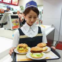 Ready to launch: A McDonald\'s employee shows off three new products during a press event earlier this month. McDonald\'s Holdings Co. Japan Ltd. announced Thursday that prices for some items will rise next month. | KYODO