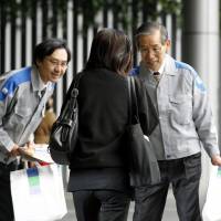 Leaving your lights on?: Kyushu Electric Power Co. officials hand out leaflets urging consumers to cut power usage by 5 percent in front of JR Hakata Station in Fukuoka on Monday. | KYODO PHOTO