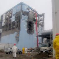 Close to the action: Workers wearing protective suits monitor water being sprayed during a cooling operation at the damaged No. 4 reactor at the Fukushima No. 1 power plant in this March 22 photo released by Tokyo Electric Power Co. | TEPCO/AP