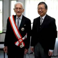 Abdelmalek Benhabyles (left) is bestowed the Grand Cordon of the Order of the Rising Sun by Japanese Ambassador Tsukasa Kawada in Algiers on Dec. 17. Below: Benhabyles (right) with Japanese supporter of Algeria Tokusaburo Dan in 1962. | EMBASSY OF ALGERIA