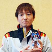 Toys for men: Junichi Nishizawa, one of the model makers at Bandai Co., holds a plastic rendering of the popular Gundam character in November. | KYODO
