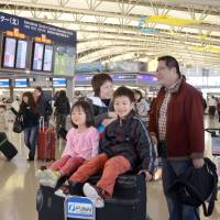 Outward bound: Children ride a luggage cart at Kansai International Airport in Osaka Prefecture as their family prepares to depart Saturday for the New Year\'s holidays, and as the outbound rush of travelers returning to their hometowns or catching flights to overseas destinations peaked. | KYODO