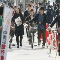 Dismount: People push their bicycles along a sidewalk designated as a \"walk zone\" in the city of Fukuoka on Monday. | KYODO