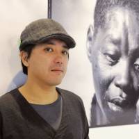 Conflict zone: Ryo Kameyama stands near one of his photos during an exhibition in Tokyo in December. | KYODO