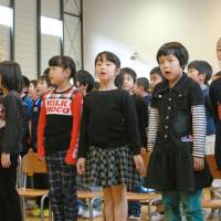 Unified: Kids in Otsuchi Elementary School in Iwate Prefecture sing their new school song Thursday in a gym in a makeshift building. | KYODO