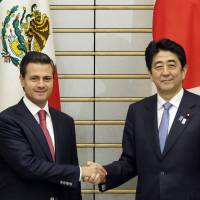 Grip and grin: Prime Minister Shinzo Abe (right) and Mexican President Enrique Pena Nieto pose at Abe\'s official residence in Tokyo on Monday. | POOL