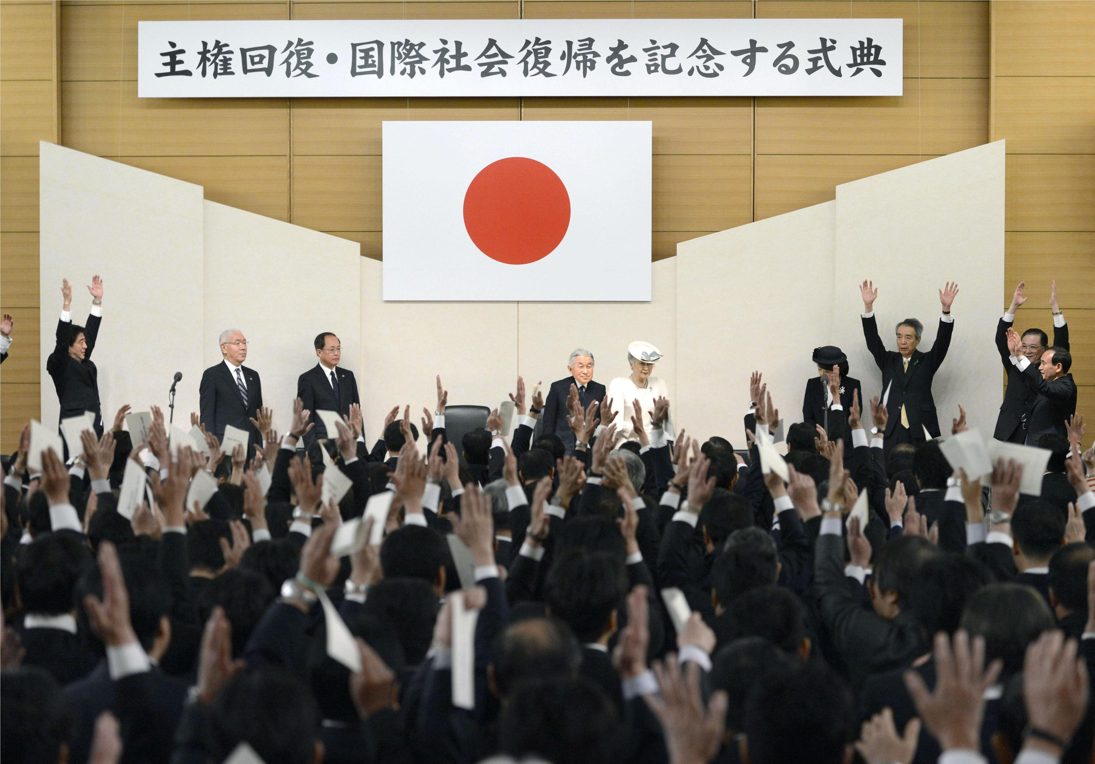 Celebrating sovereignty: Prime Minister Shinzo Abe (far left) and other conservative members of the Liberal Democratic Party raise a banzai cheer at a ceremony in Tokyo on Sunday marking the return of Japan's sovereignty following the signing of the San Francisco Peace Treaty in 1951. At center stage, Emperor Akihito and Empress Michiko look on. | KYODO