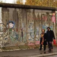 Off the wall: Pedestrians pass in front of a remaining section of the Berlin Wall in November 2005. Chunks of the Iron Curtain icon are now displayed at the headquarters of the U.N. in New York, at a casino in Las Vegas and at Microsoft\'s headquarters in Washington state. | THE WASHINGTON POST