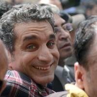 Reason to smile: Egyptian satirist and television host Bassem  Youssef is surrounded by supporters upon his arrival at the high court public prosecutor\'s office at the high court in Cairo on March 31. | AFP-JIJI