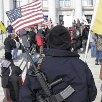 Strapped: A firearms rights advocate carries an AR-15 with a U.S. flag in the barrel outside the Utah state Capitol in Salt Lake City during a Gun Appreciation Day Rally in January. | AP