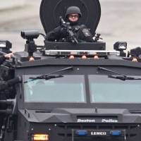 Heavily armed police patrol a neighborhood in the suburb while riding on an armored Humvee the same day. | AP