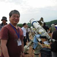 A member of the Tegahoshimitai astronomy group of Kashiwa City, Chiba Prefecture, proudly stands next a collection of telescopes specially prepared for the event.  | Sofia Elghazzali