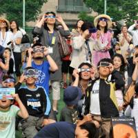 Parents, teachers and students at Honmura Elementary School in Minato Ward, Tokyo, delight in seeing a rare solar eclipse. | Yoshiaki Miura 