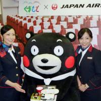 Japan Airlines cabin attendants pose with Kumamoto Prefecture\'s popular black bear mascot, Kumamon, in Ota Ward, Tokyo, on Thursday. JAL says it will serve \"Air Kumamon\" meals featuring local Kumamoto dishes on some international flights from June 1 to Aug. 31. | KYODO