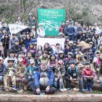 All smiles: Volunteers from Higashi Matsushima pose with he they call \"Uncle Nic\" below the overgrown slope up which the Tree Dragon now rears. | CONAN WAKELY