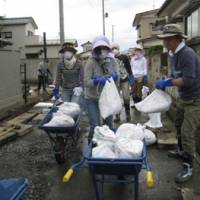 Mucking in: Volunteers from the Shangri-La Hotel Tokyo shift bags of sludge they dug out of drainage gutters in Ishinomaki, Miyagi Prefecture, on Tuesday. | TOMOKO OTAKE PHOTOS