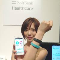 Wrist strong: A model wears a Fitbit flex wristband that can send health and fitness information to a Softbank smartphone. | KAZUAKI NAGATA